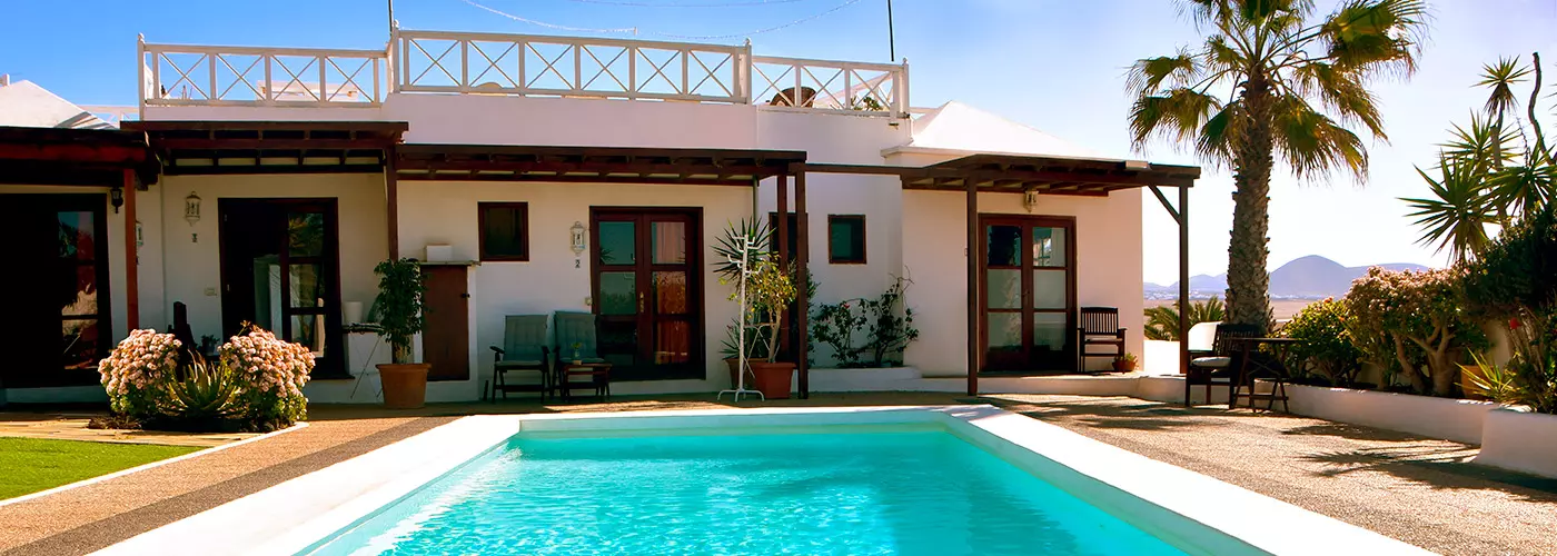 luxuriöse Villa mit Pool, Palmen und Bergblick bei klarem Himmel