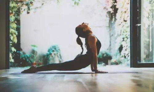Frau praktiziert Yoga vor Gartentüren