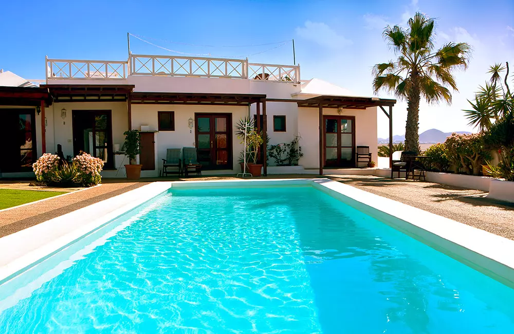 luxuriöse Villa mit Pool, Palmen und Bergblick bei klarem Himmel