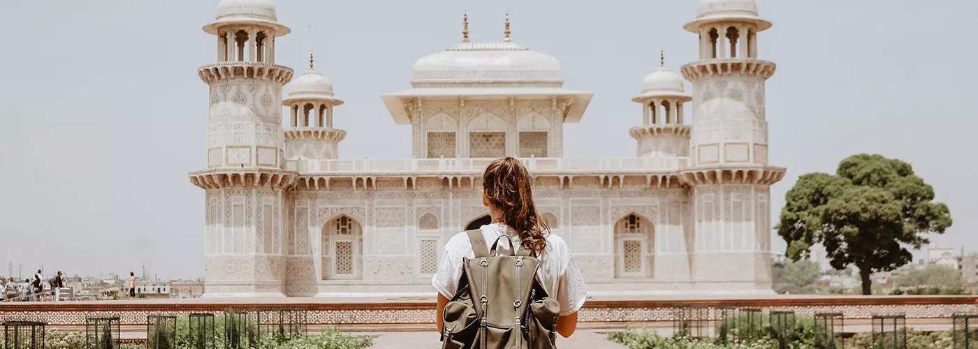 junge Frau mit Rucksack steht vor dem Itimad-ud-Daula-Mausoleum